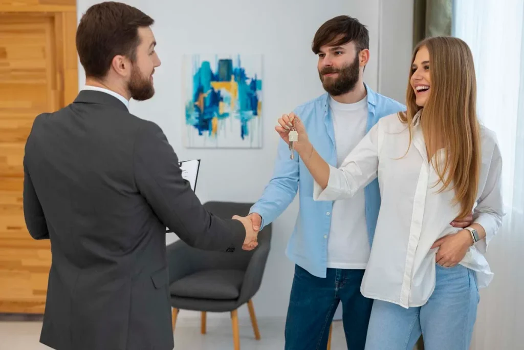 Bright and welcoming property manager in a modern living room with homeowners handing the keys