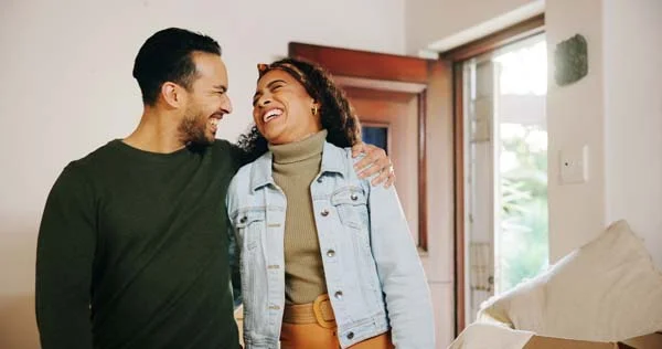 Excited couple smiling and opening the front door of their home