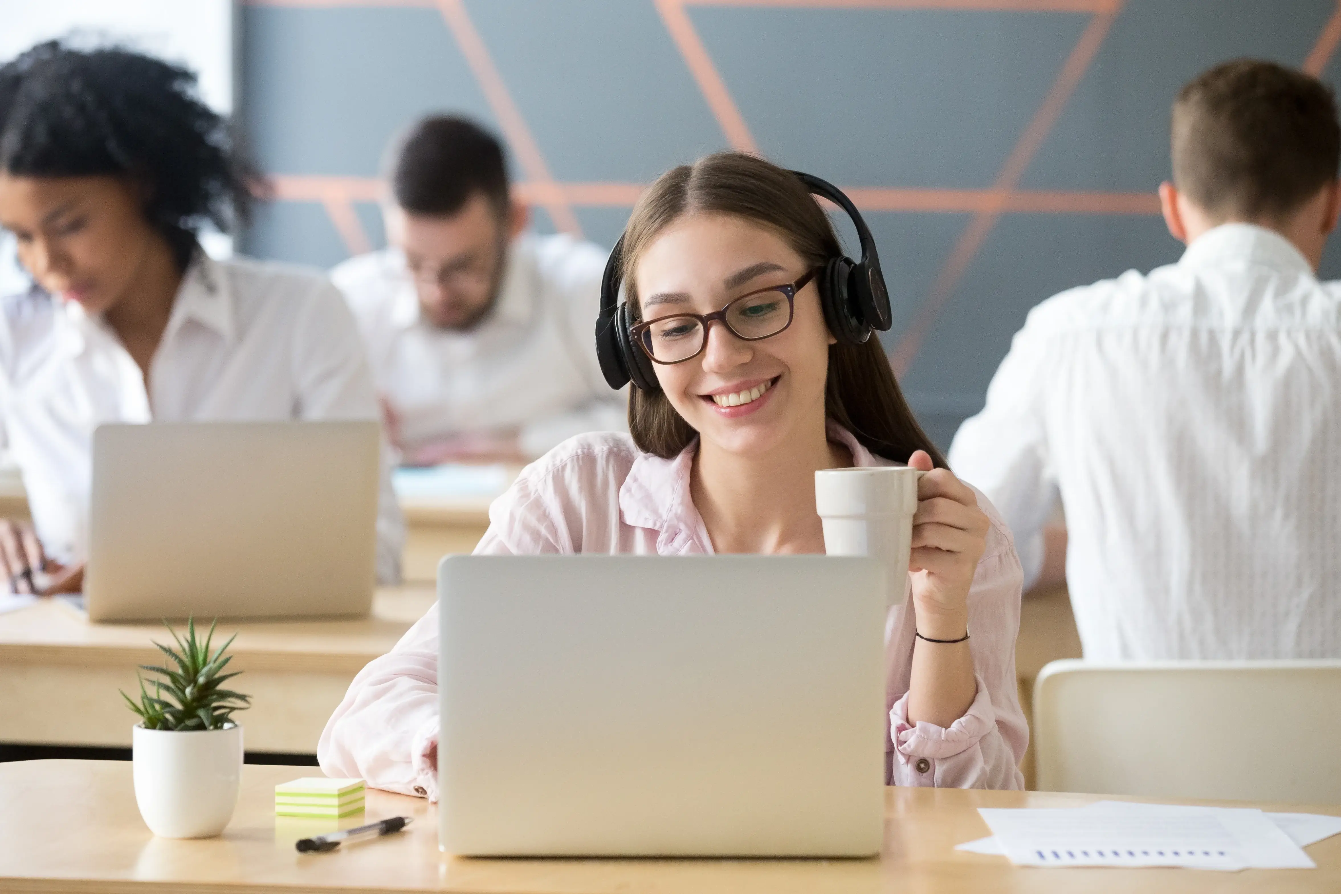 Friendly guest support agent wearing a headset and smiling while working on a laptop.