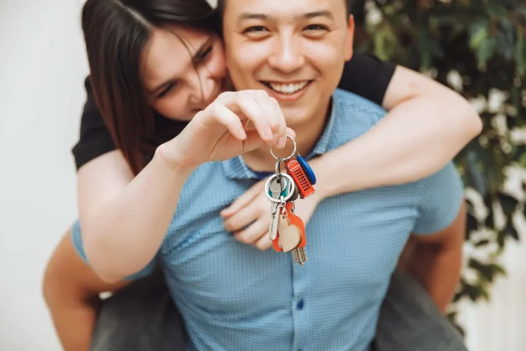 Happy homeowners holding house keys in front of their coastal vacation rental