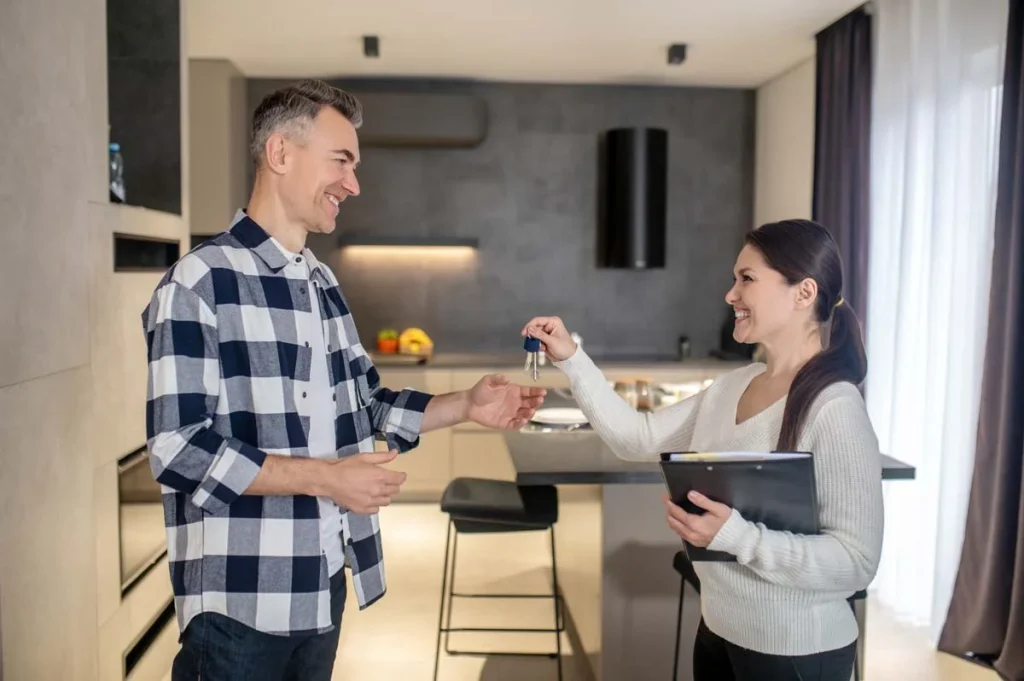 Property manager handing keys to a homeowner in front of an entrance