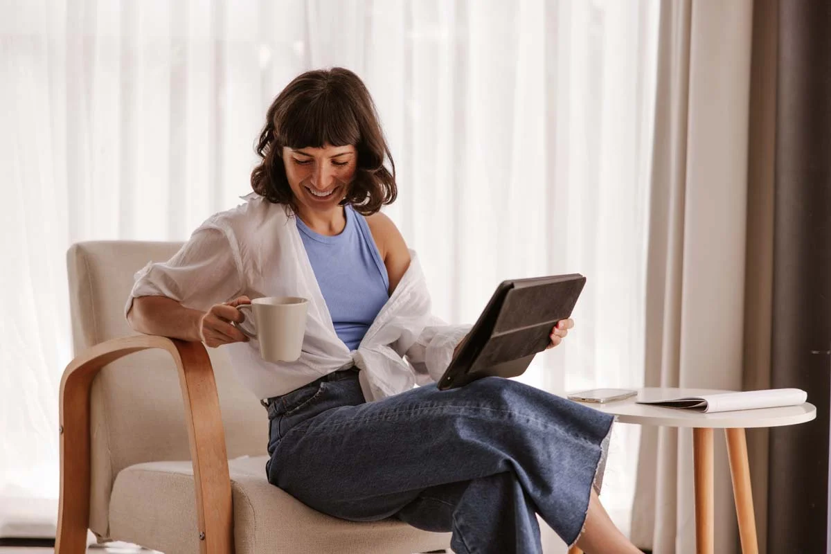 Relaxed rental property owner drinking coffee and looking at a tablet