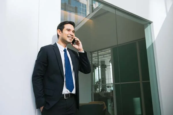 Smiling businessman talking on the phone in a modern office hallway