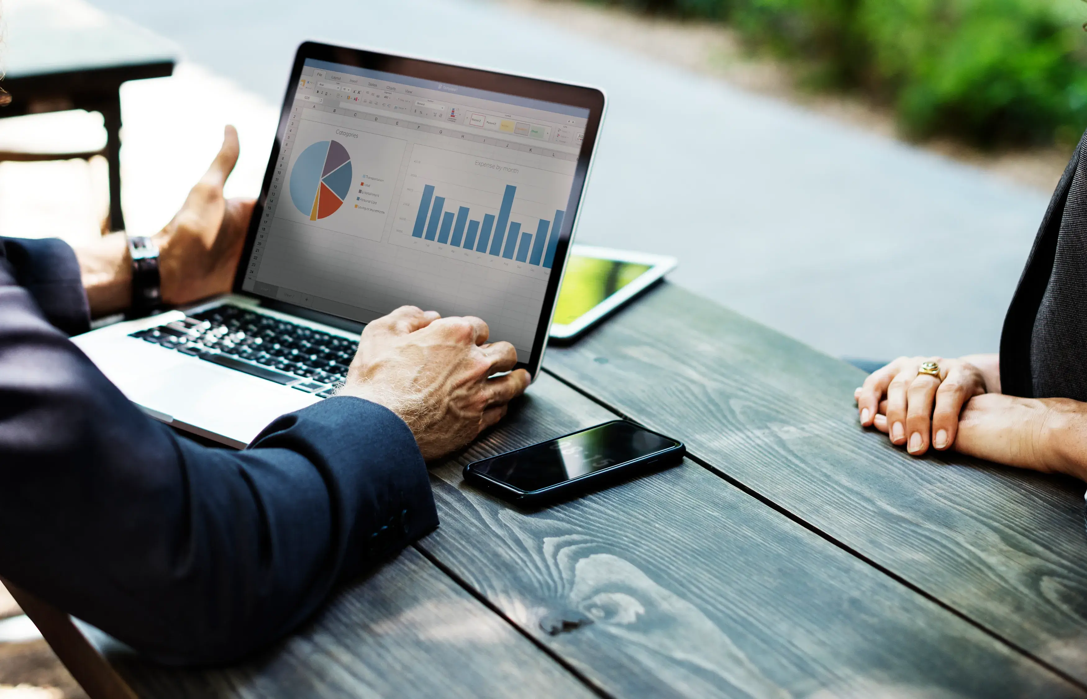Two business professionals discussing revenue through graphs and charts displayed on a laptop