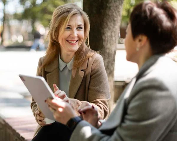 Two professional colleagues smiling and reviewing information on a digital tablet