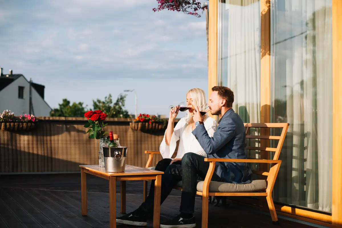 A couple sitting by a large window enjoys drinks and snacks, looking out at a scenic view of the city
