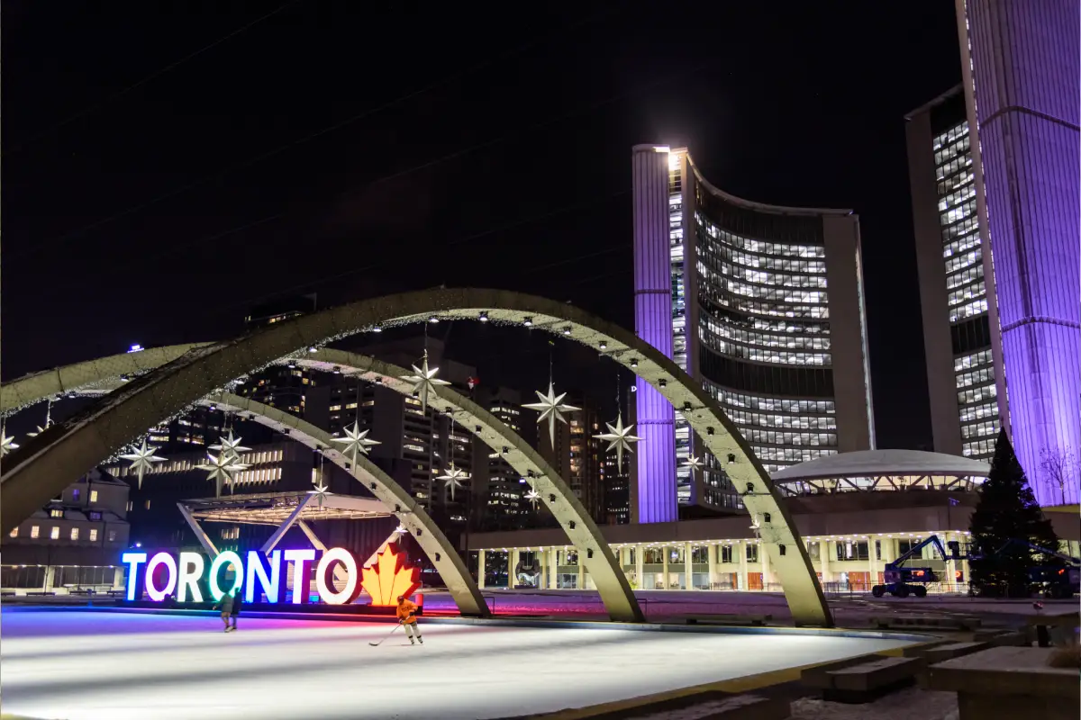 Front entrance of the Metro Toronto Convention Centre under a bright glass canopy at twilight.