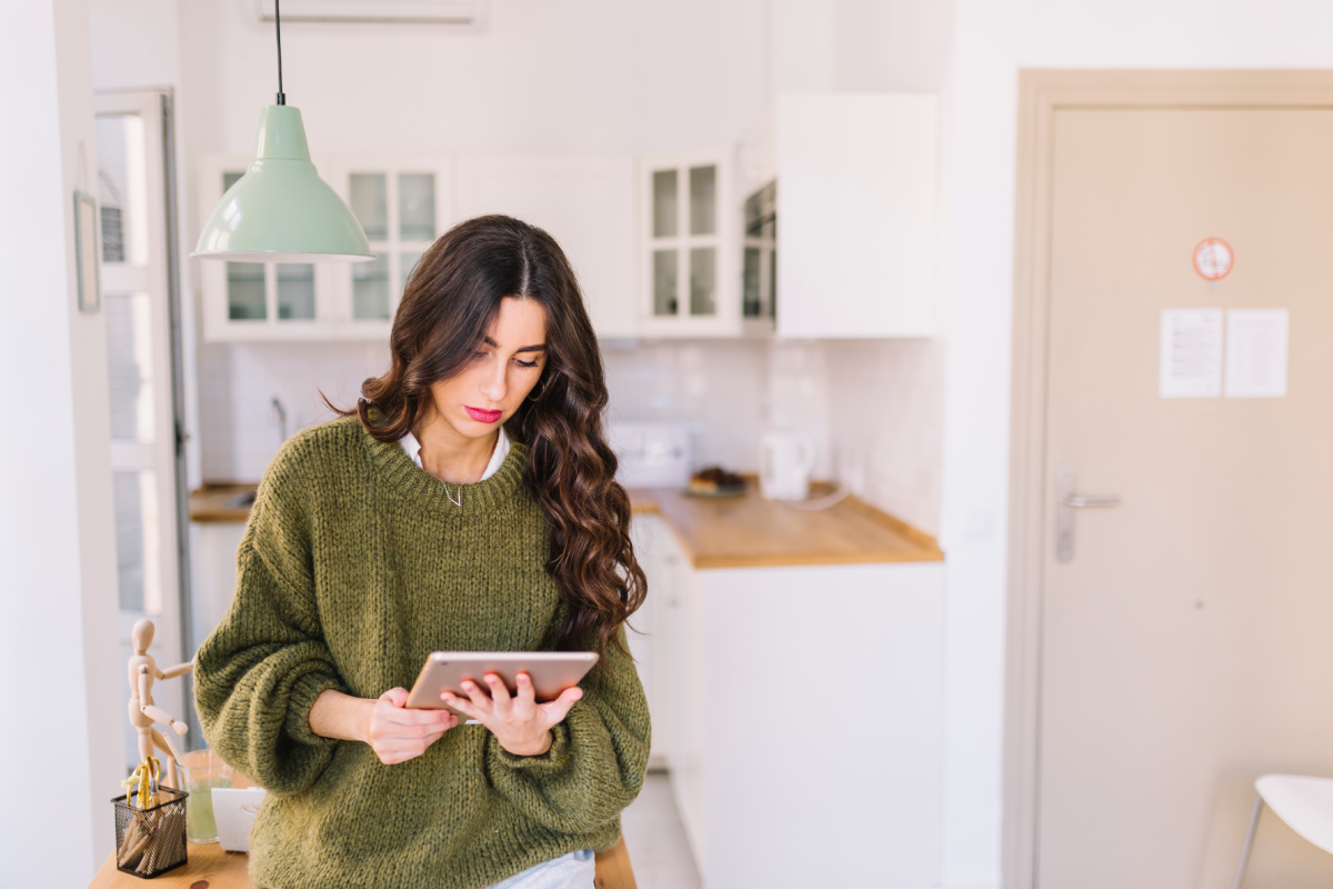 Vacation rental owner using a tablet to inspect a living room before guest check-in.